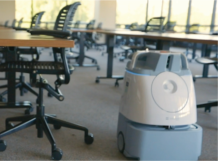 Robot vacuum cleaning an empty office space.