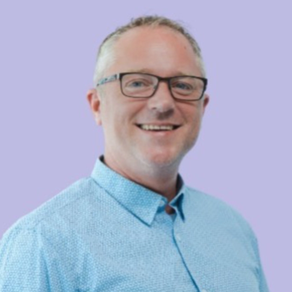 Smiling man with glasses and blue shirt