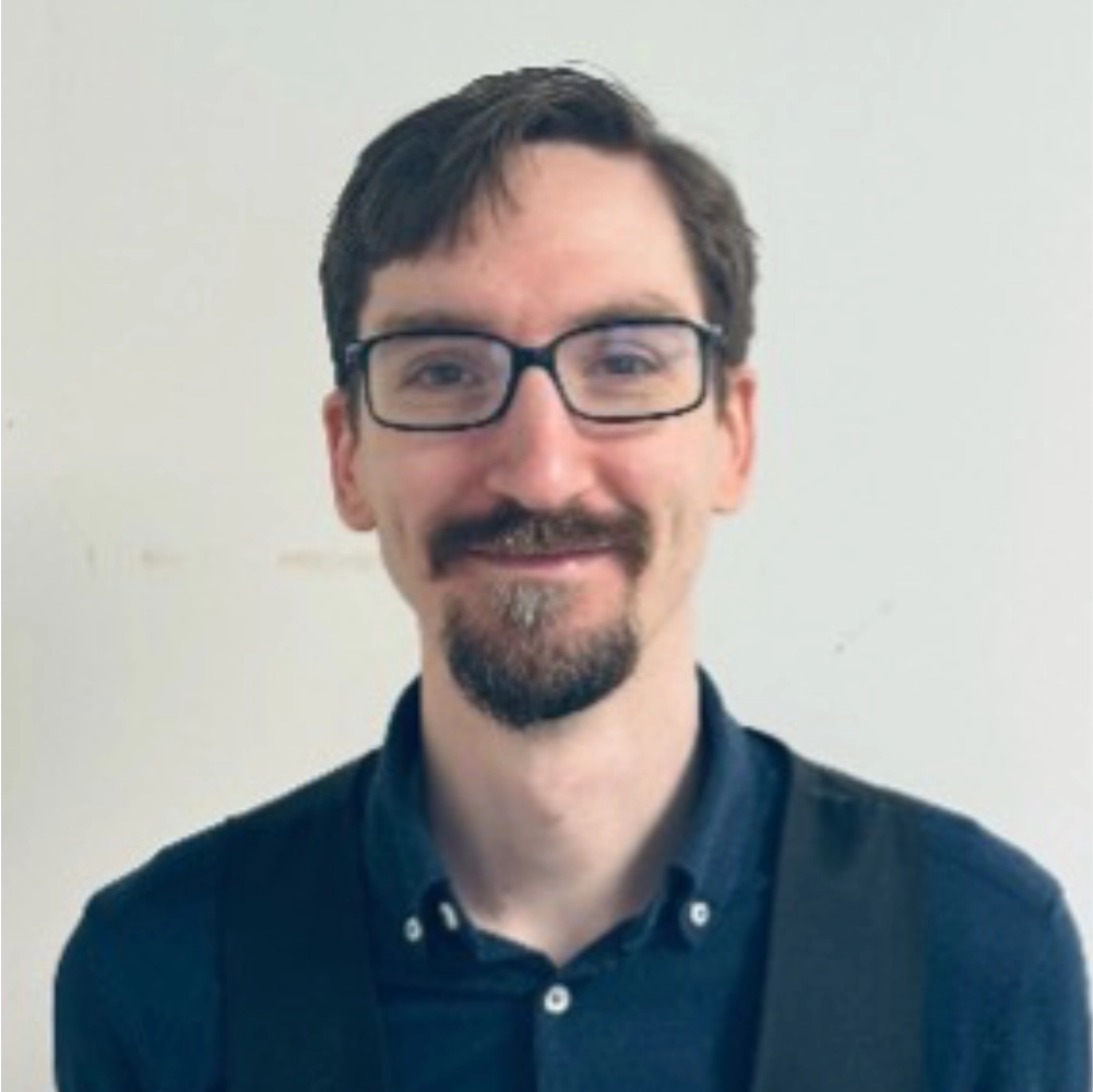 Smiling man with glasses and beard.